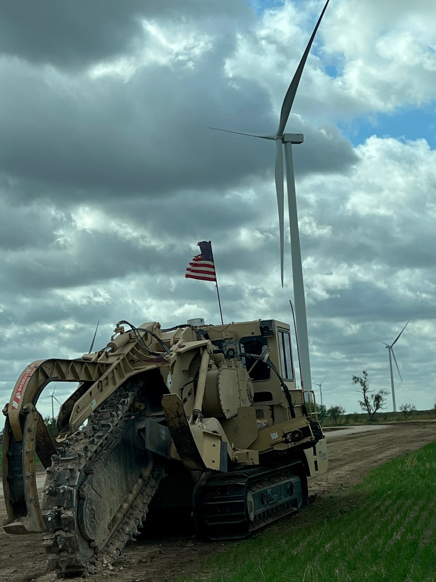 flag on top of construction equipment with wind mill in background